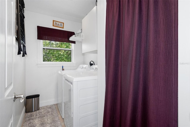 laundry room featuring baseboards, cabinet space, and independent washer and dryer