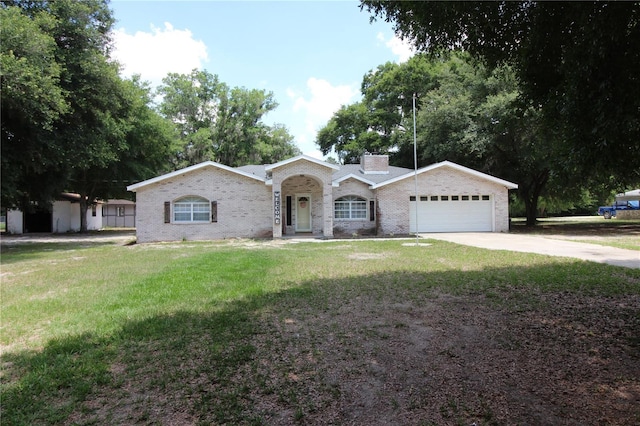 single story home featuring a front yard, concrete driveway, a chimney, brick siding, and a garage