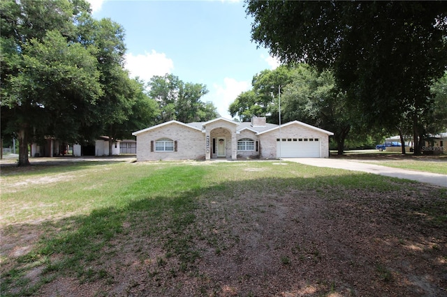 ranch-style home with driveway, a chimney, a garage, and a front yard