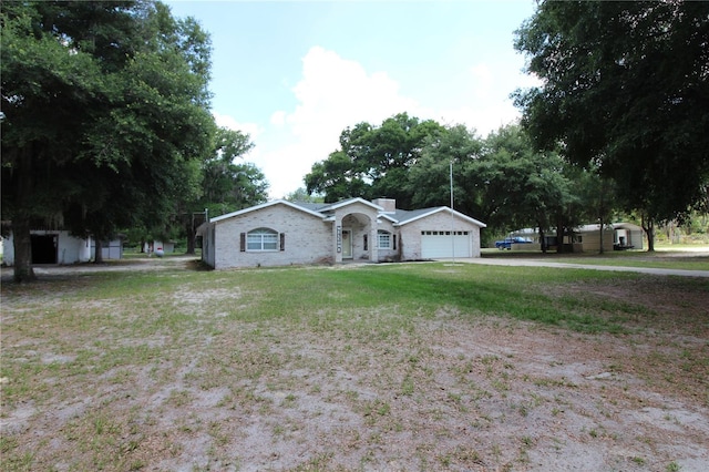 single story home featuring an attached garage, a chimney, and a front yard