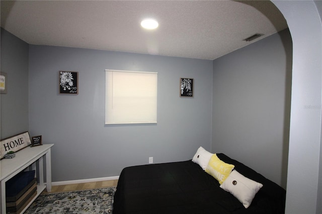 bedroom featuring baseboards, visible vents, and arched walkways