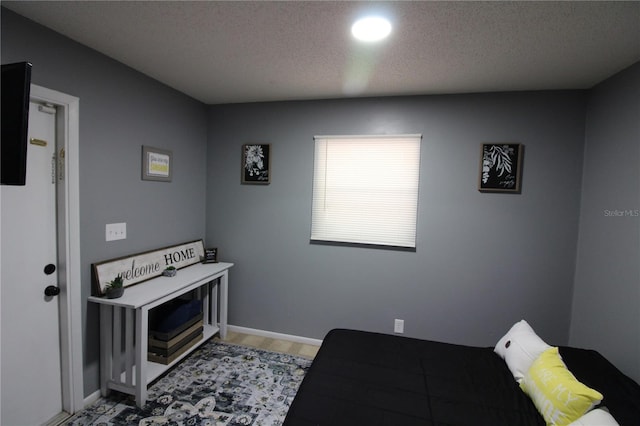 bedroom featuring light wood-style flooring, baseboards, and a textured ceiling