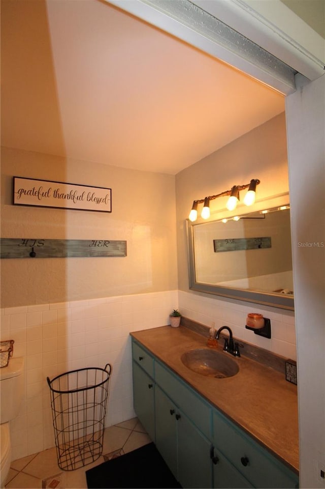 half bath with vanity, tile walls, toilet, a wainscoted wall, and tile patterned floors