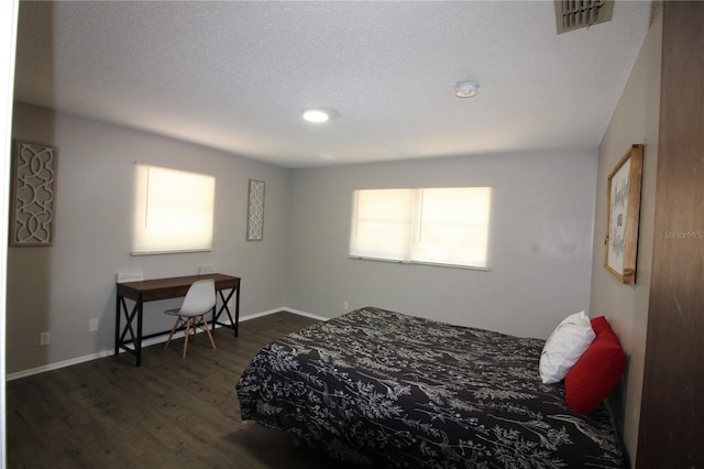 bedroom with baseboards, a textured ceiling, dark wood-style floors, and visible vents