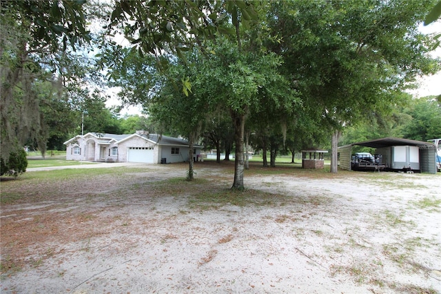 view of yard featuring a garage and a carport
