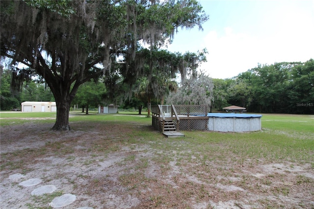 view of yard featuring a wooden deck, an outdoor structure, a storage shed, and an outdoor pool