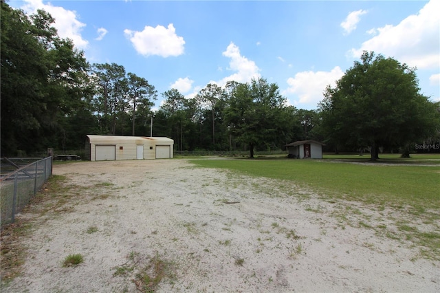 view of yard featuring an outbuilding, fence, a detached garage, and a storage shed