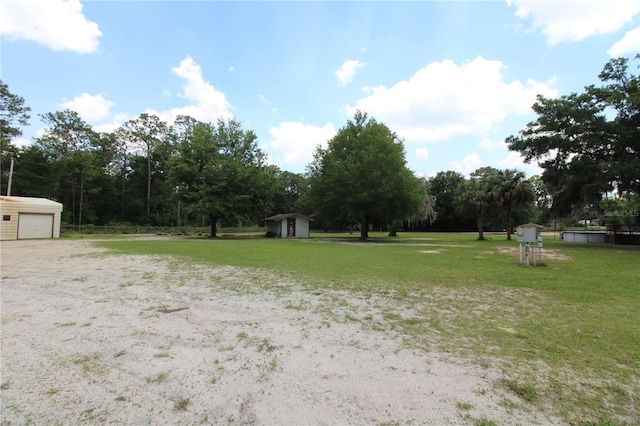 view of yard featuring an outbuilding, a storage unit, and a detached garage