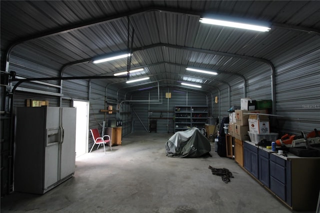 garage featuring metal wall and white fridge with ice dispenser