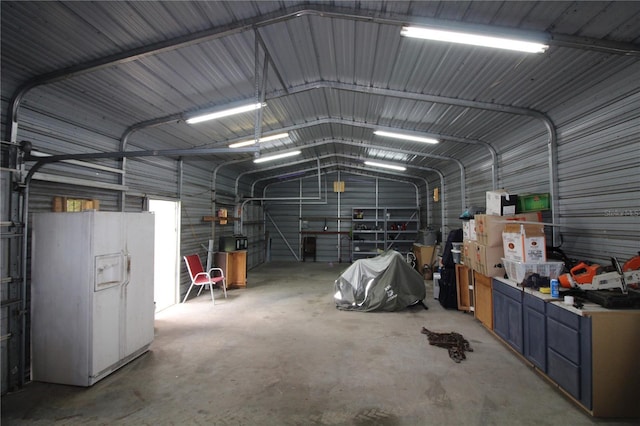 garage with metal wall and white refrigerator with ice dispenser