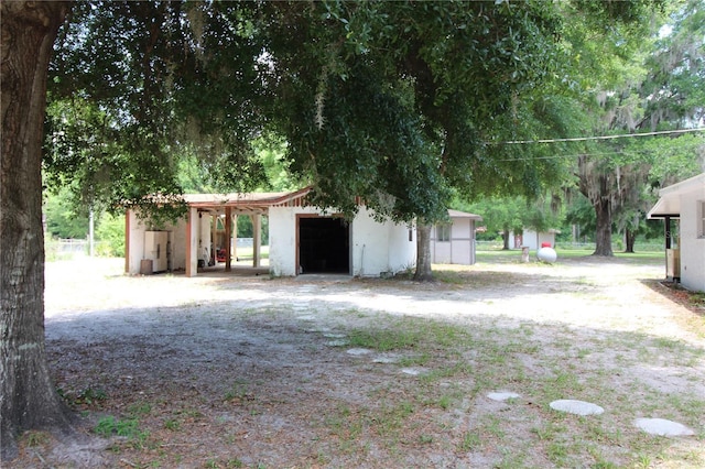 exterior space with dirt driveway, an outbuilding, and a detached garage