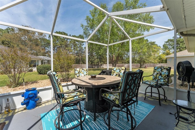 view of patio featuring fence, outdoor dining space, and a lanai