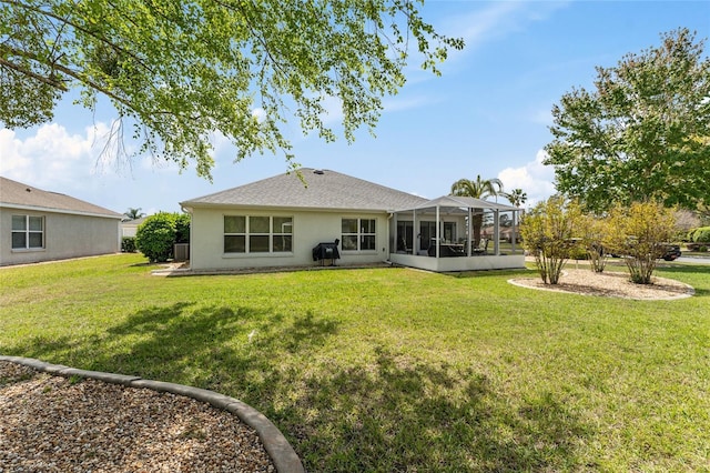back of house with a lawn, a sunroom, and stucco siding