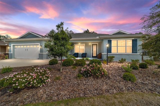 single story home featuring driveway, stucco siding, a porch, and a garage