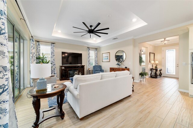 10445 SW 90th Street Rd, Ocala, FL 34481 - living room featuring a tray ceiling, healthy amount of natural light, crown molding, ceiling fan, and light wood-type flooring