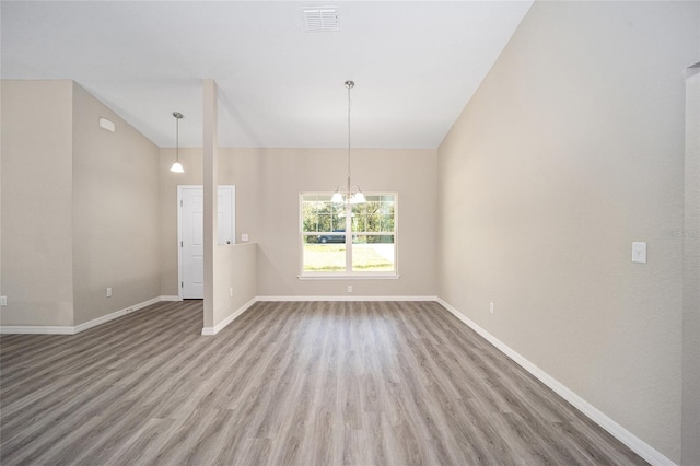 unfurnished room with wood finished floors, a notable chandelier, baseboards, and visible vents