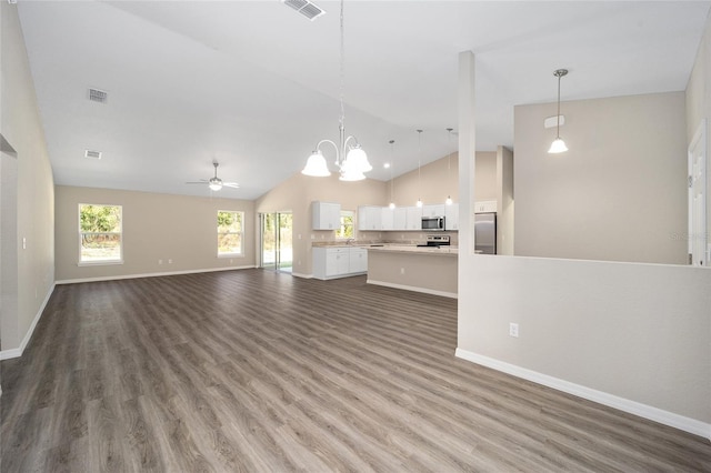 unfurnished living room with baseboards, visible vents, ceiling fan with notable chandelier, and wood finished floors