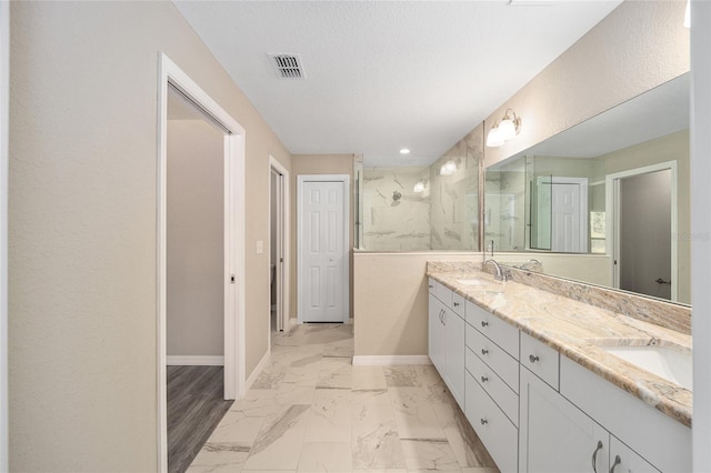full bath with visible vents, baseboards, marble finish floor, double vanity, and a marble finish shower