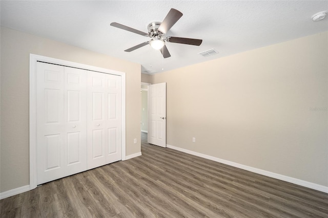 unfurnished bedroom featuring a closet, visible vents, baseboards, wood finished floors, and a ceiling fan