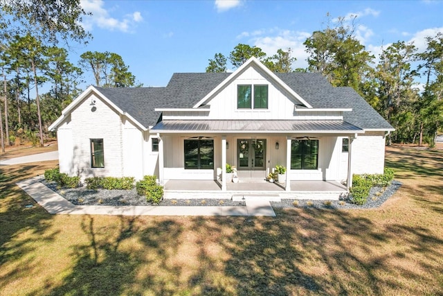 5024 N Tumblewood Dr, Crystal River, FL 34428 - rear view of property featuring covered porch, a standing seam roof, french doors, a shingled roof, and a lawn