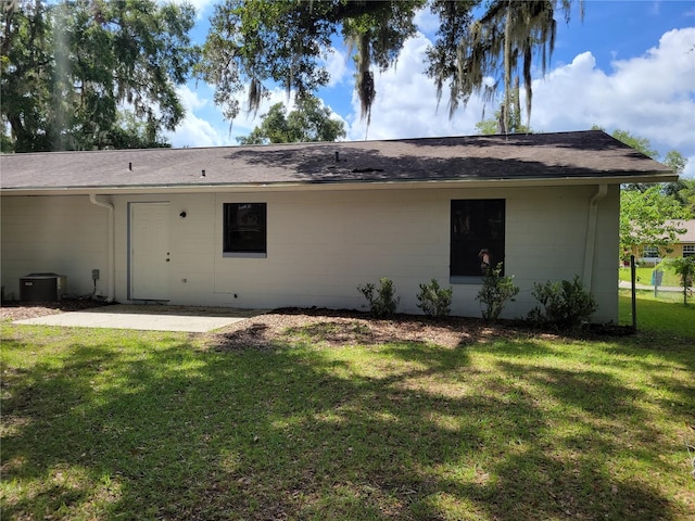 707/709 NE 26th St, Ocala, FL 34470 - rear view of property featuring central AC, concrete block siding, a shingled roof, a yard, and a patio area