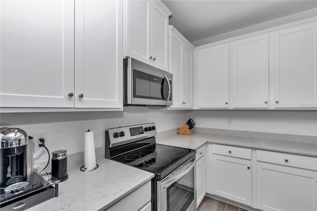 9312 SW 58th Cir, Ocala, FL 34476 - kitchen with appliances with stainless steel finishes, white cabinetry, light stone counters, and light wood-style floors