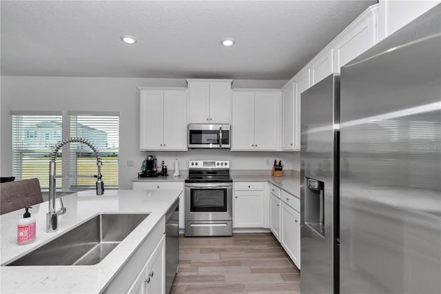 9312 SW 58th Cir, Ocala, FL 34476 - kitchen featuring a sink, appliances with stainless steel finishes, light wood-type flooring, recessed lighting, and white cabinetry