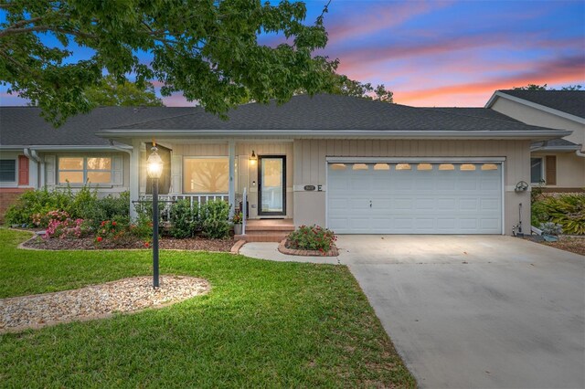 8645 SW 94th Ln Unit E, Ocala, FL 34481 - ranch-style house featuring an attached garage, covered porch, a front lawn, driveway, and roof with shingles