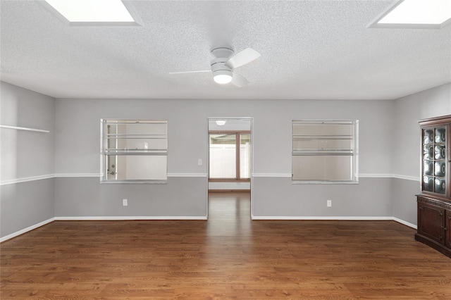 8645 SW 94th Ln Unit E, Ocala, FL 34481 - empty room with a skylight, baseboards, a textured ceiling, ceiling fan, and wood finished floors
