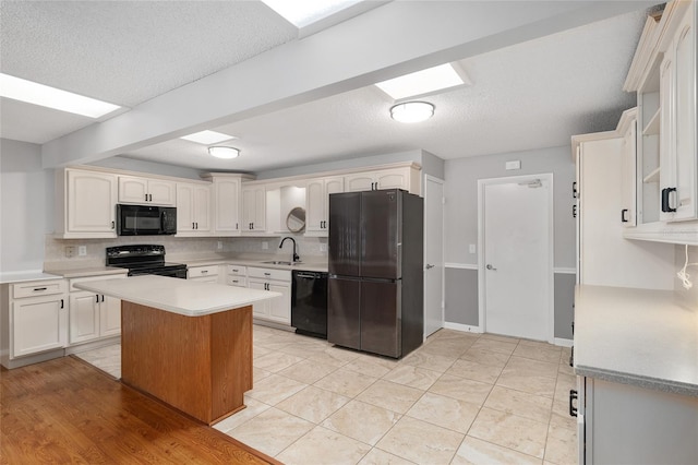 8645 SW 94th Ln Unit E, Ocala, FL 34481 - kitchen with a textured ceiling, black appliances, light countertops, a sink, and decorative backsplash