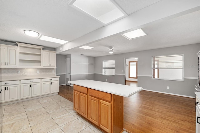 8645 SW 94th Ln Unit E, Ocala, FL 34481 - kitchen featuring tasteful backsplash, light countertops, a ceiling fan, open shelves, and a kitchen island