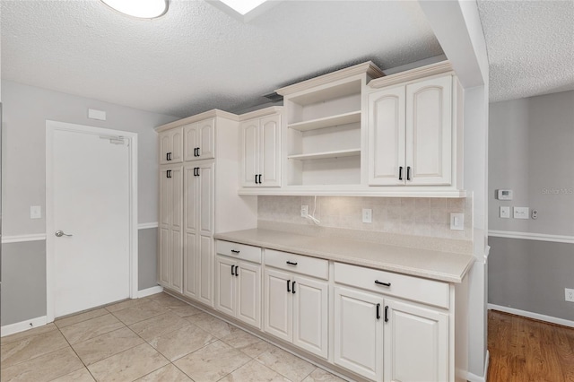 8645 SW 94th Ln Unit E, Ocala, FL 34481 - kitchen featuring tasteful backsplash, a textured ceiling, open shelves, light countertops, and baseboards