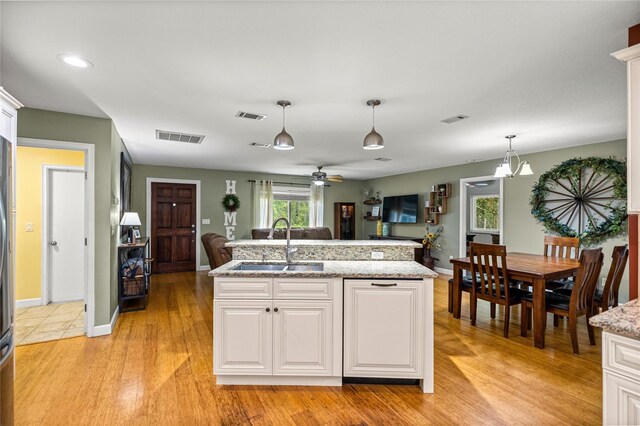 5118 SW 197th Ter, Dunnellon, FL 34431 - kitchen featuring a sink, hanging light fixtures, light wood finished floors, white cabinets, and open floor plan