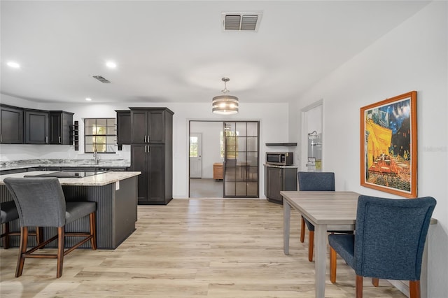 6549 NW 65th Pl, Ocala, FL 34482 - kitchen with stainless steel microwave, a kitchen bar, light wood finished floors, and visible vents