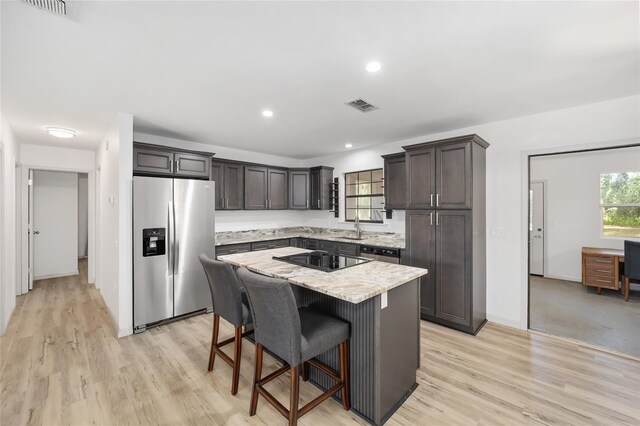 6549 NW 65th Pl, Ocala, FL 34482 - kitchen with a breakfast bar, a kitchen island, light stone counters, visible vents, and appliances with stainless steel finishes