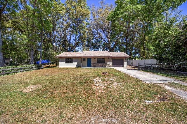 6549 NW 65th Pl, Ocala, FL 34482 - ranch-style house with stone siding, fence, an attached garage, a front yard, and driveway