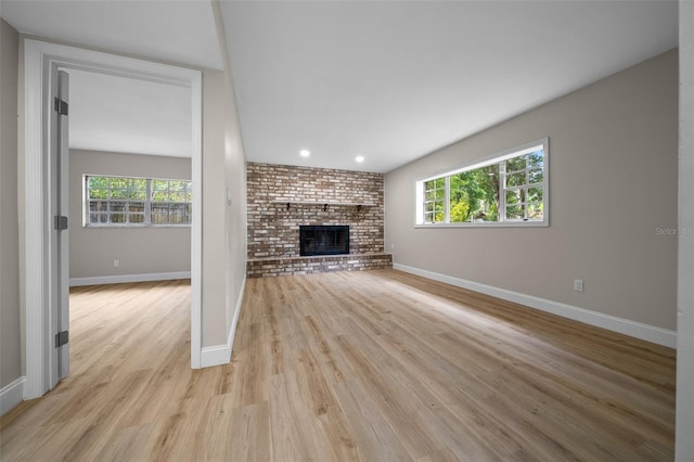 341 SE 53rd Ct, Ocala, FL 34480 - unfurnished living room with baseboards, a wealth of natural light, a fireplace, and light wood finished floors