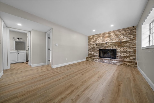 341 SE 53rd Ct, Ocala, FL 34480 - unfurnished living room featuring a sink, baseboards, light wood-style floors, and a fireplace