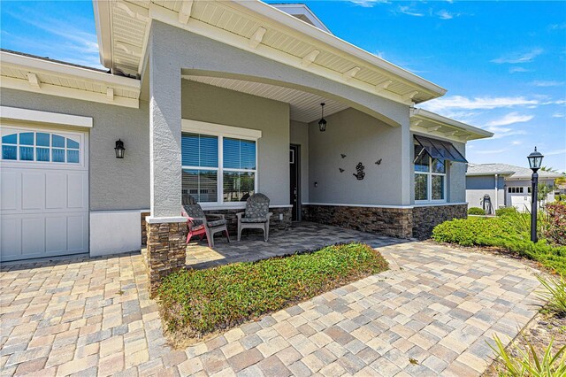 9342 SW 102nd Terrace Rd, Ocala, FL 34481 - view of exterior entry featuring stucco siding, an attached garage, and stone siding