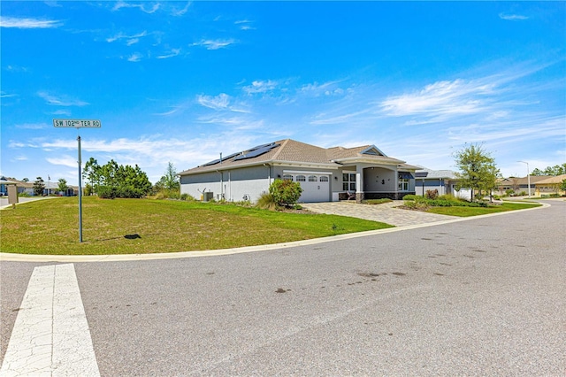 9342 SW 102nd Terrace Rd, Ocala, FL 34481 - view of front of house featuring driveway, a front yard, stucco siding, solar panels, and a garage