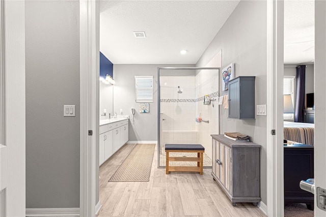 9342 SW 102nd Terrace Rd, Ocala, FL 34481 - ensuite bathroom with vanity, a shower stall, wood finished floors, a textured ceiling, and baseboards
