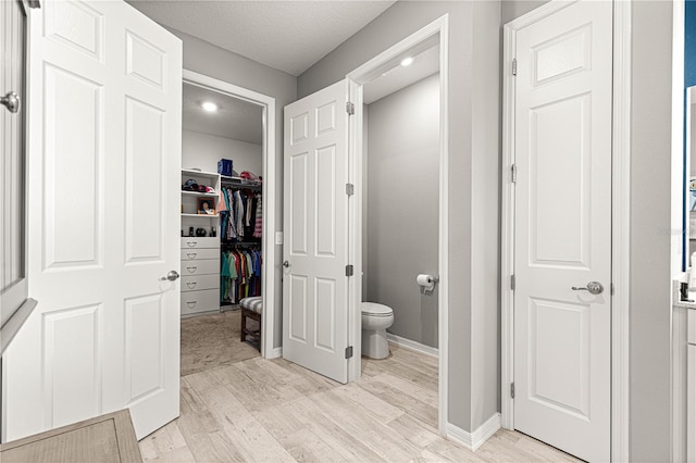 9342 SW 102nd Terrace Rd, Ocala, FL 34481 - bathroom featuring a textured ceiling, baseboards, wood finished floors, toilet, and a walk in closet