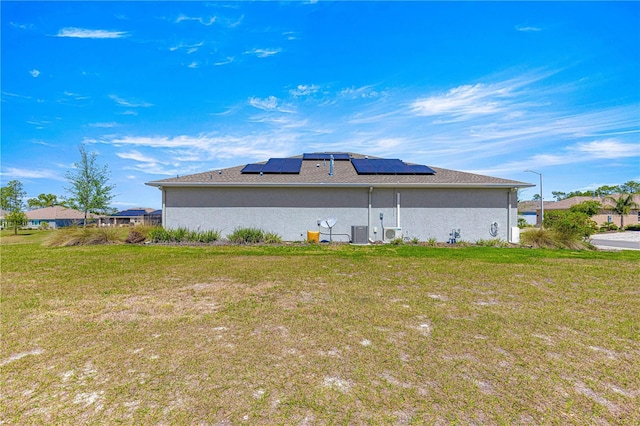 9342 SW 102nd Terrace Rd, Ocala, FL 34481 - back of house featuring stucco siding, central air condition unit, roof mounted solar panels, and a yard