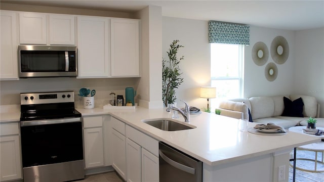 6579 SW 81st Loop, Ocala, FL 34476 - kitchen featuring open floor plan, a sink, white cabinets, a peninsula, and appliances with stainless steel finishes