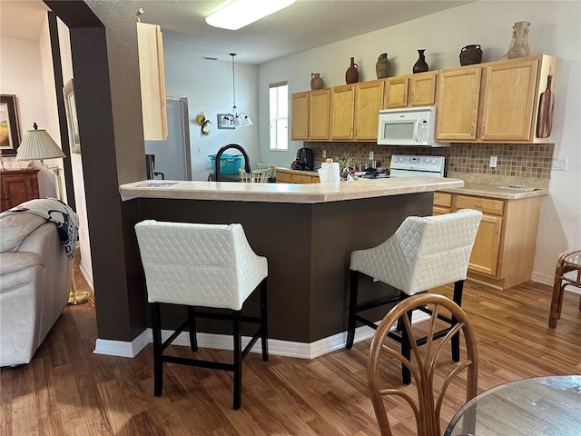 9053 SW 103rd Ave, Ocala, FL 34481 - kitchen with white appliances, a kitchen bar, dark wood-style floors, and light brown cabinets