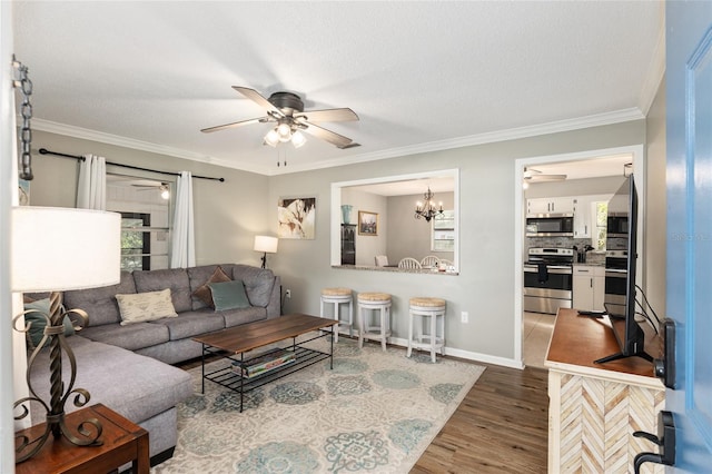 6830 NW 62nd Pl, Ocala, FL 34482 - living room featuring ceiling fan with notable chandelier, crown molding, wood finished floors, and baseboards