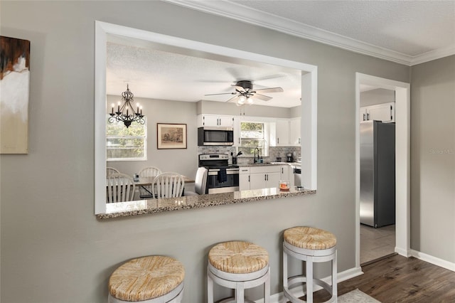 6830 NW 62nd Pl, Ocala, FL 34482 - kitchen featuring a kitchen breakfast bar, backsplash, a sink, white cabinets, and appliances with stainless steel finishes