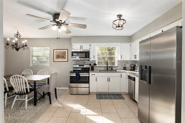 6830 NW 62nd Pl, Ocala, FL 34482 - kitchen with backsplash, a sink, light tile patterned floors, stainless steel appliances, and white cabinets