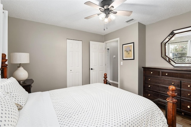 6830 NW 62nd Pl, Ocala, FL 34482 - bedroom with a closet, a textured ceiling, visible vents, wood finished floors, and a ceiling fan