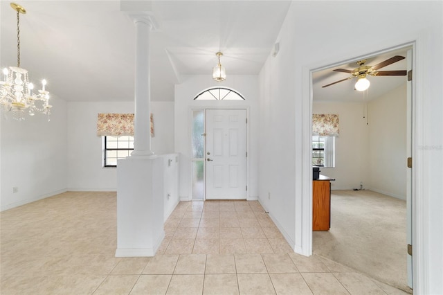 foyer featuring ornate columns, vaulted ceiling, a ceiling fan, a chandelier, and light tile patterned floors
